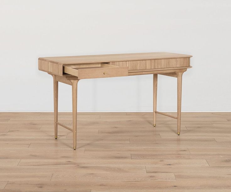 a wooden desk sitting on top of a hard wood floor next to a white wall