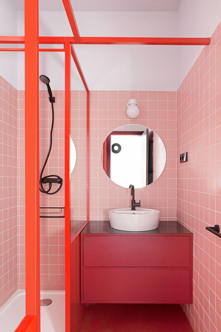 a bathroom with pink and red tiles on the walls