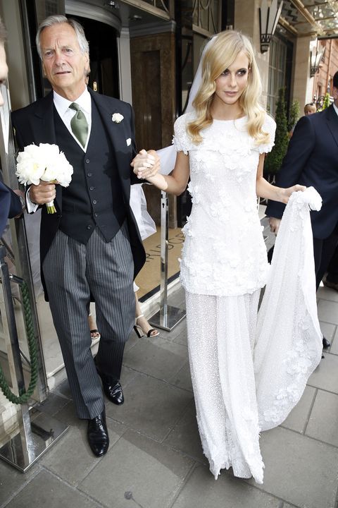 a man and woman are walking down the street with white flowers in their hand,