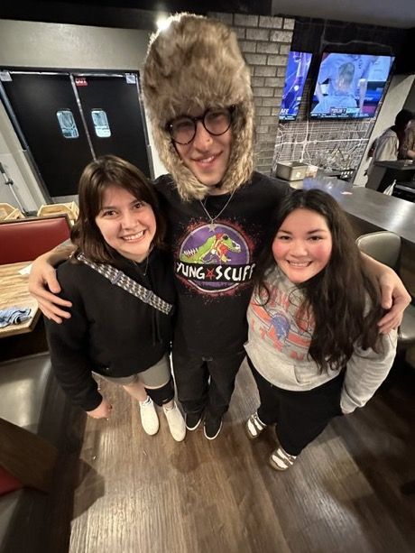 two girls and a man are posing for the camera