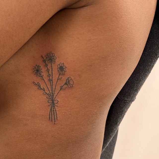 a woman's back with flowers tattoo on her left side ribcadings