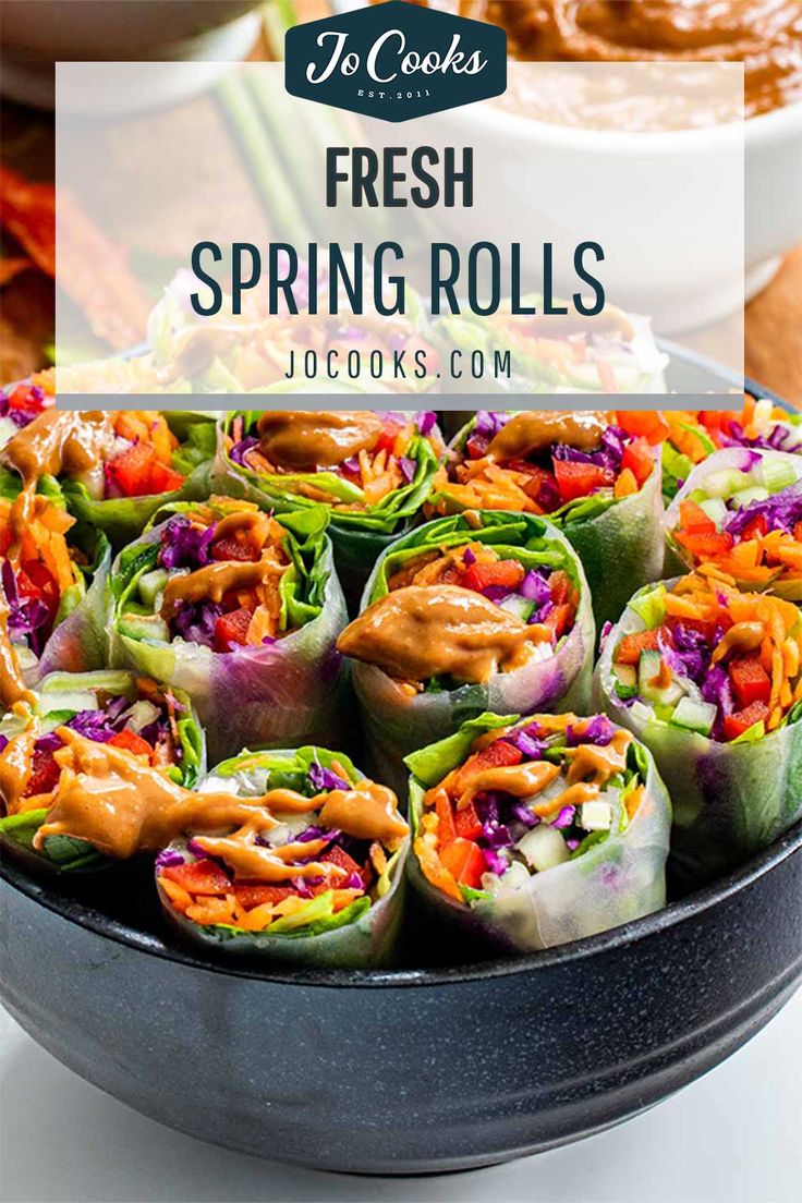 fresh spring rolls in a pan with dipping sauce on the side and other food items