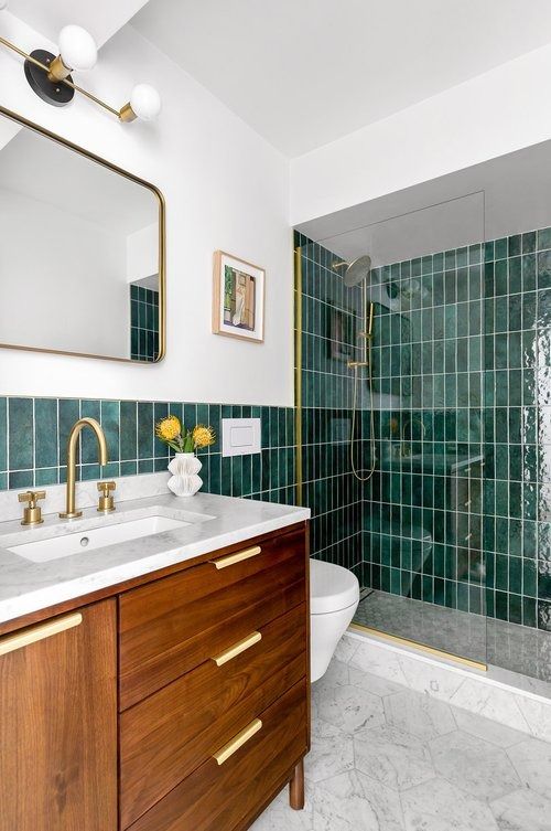 a bathroom with green tile and wooden cabinets