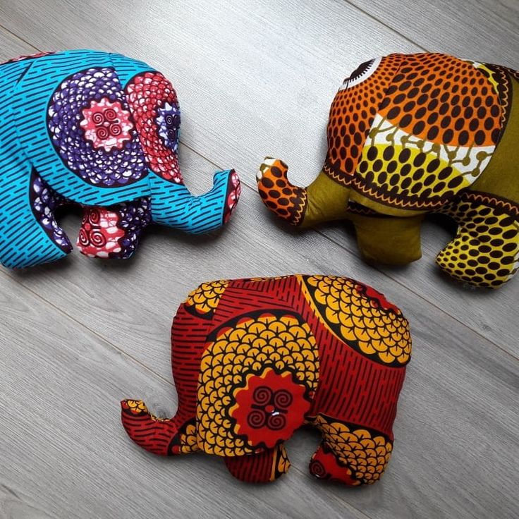 three colorfully painted elephants sitting on top of a wooden floor