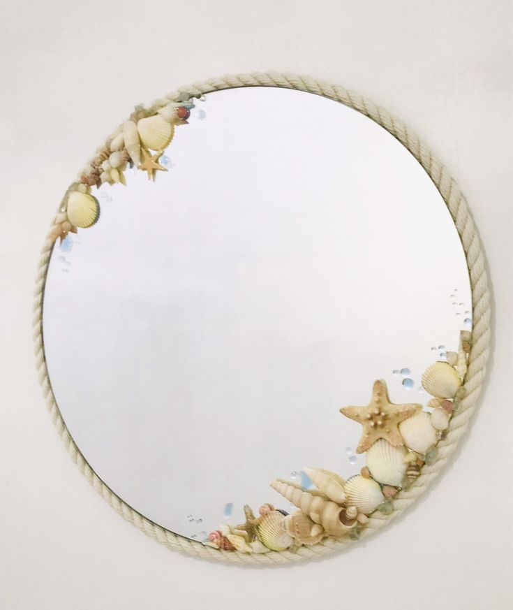 a round mirror with seashells and starfish on the rope in front of it