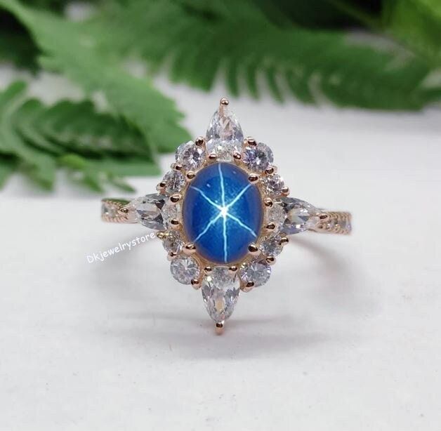 a close up of a ring with a blue star in the center surrounded by diamonds