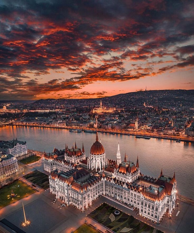 an aerial view of a large building in the middle of a river at sunset or dawn