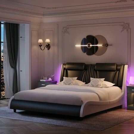 a large bed sitting in the middle of a bedroom next to a window with city lights on it