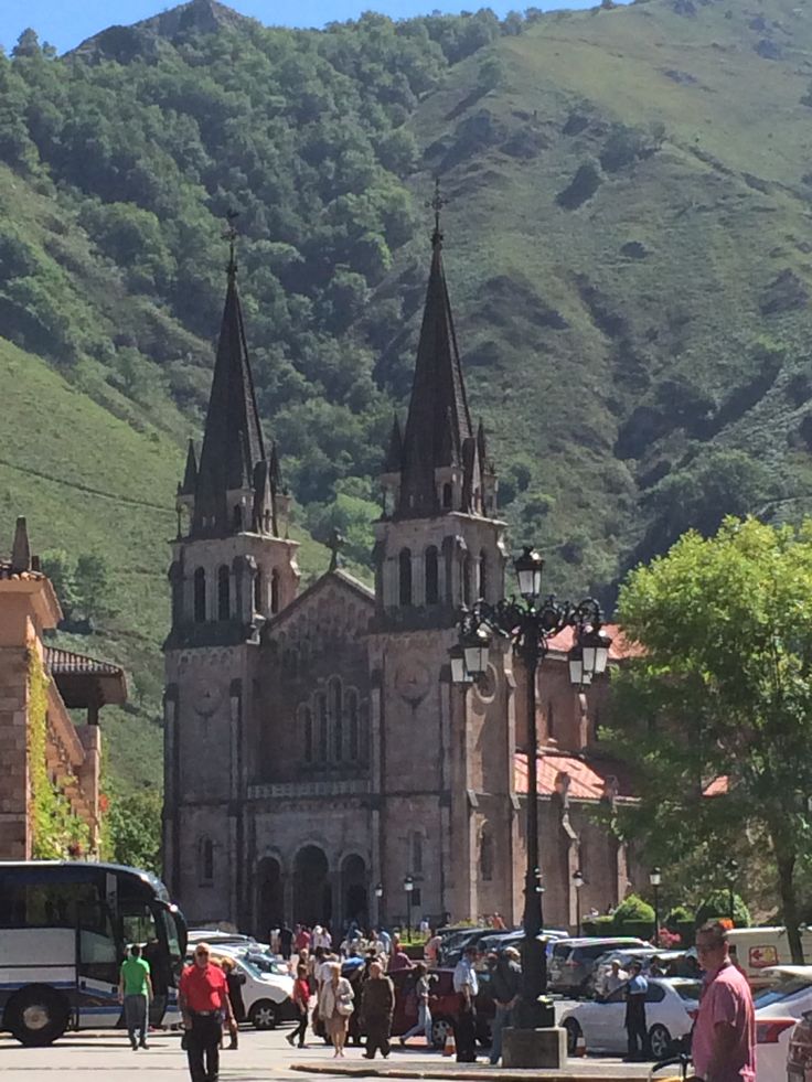 people are walking down the street in front of an old church