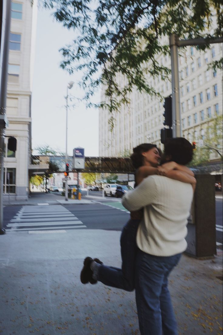 two people hugging each other on the street