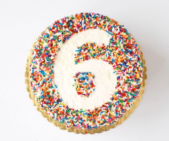 a cake with sprinkles and the number six on it's top