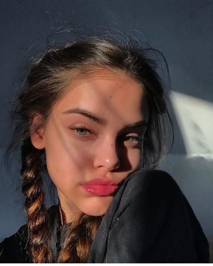 a young woman with braids is posing for the camera