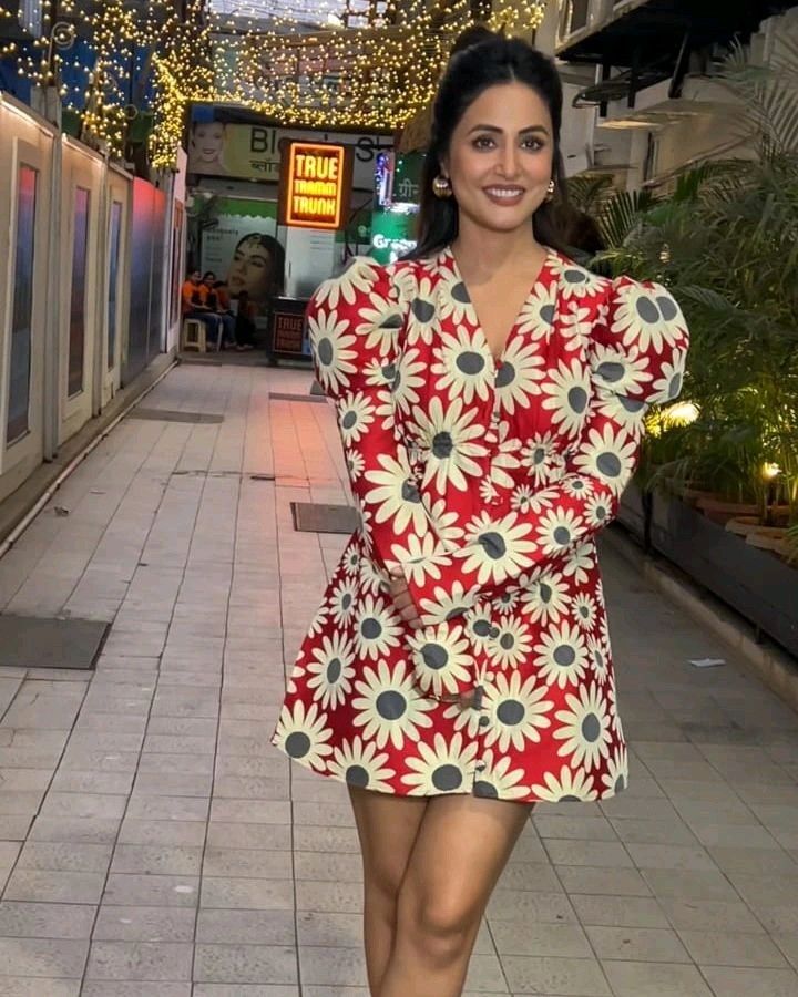 a woman in a red and white dress is walking down the street with her hands on her hips