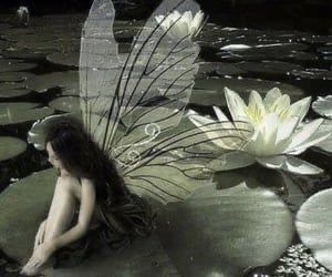 a woman sitting on top of a lily pad next to a white flower in the water