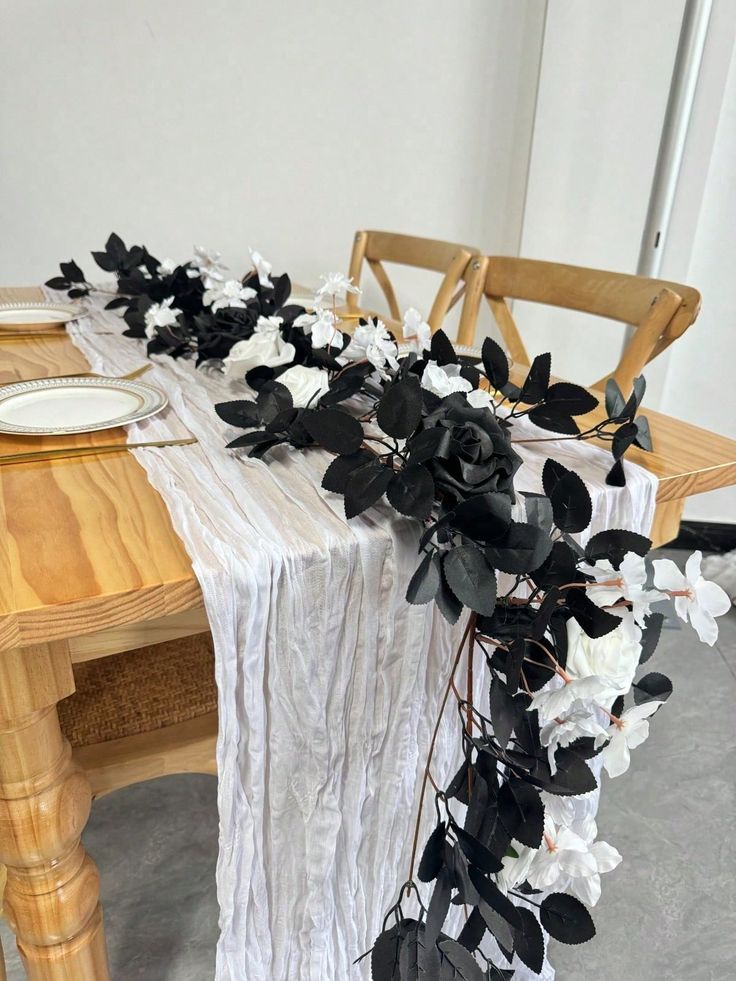 the table is set with black and white flowers on it, along with a wooden chair