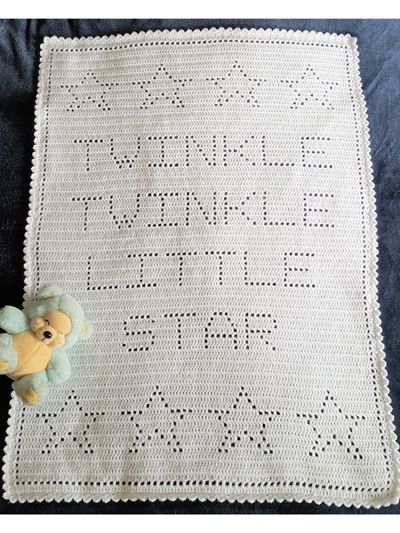 a teddy bear sitting on top of a white crocheted blanket with words written across it