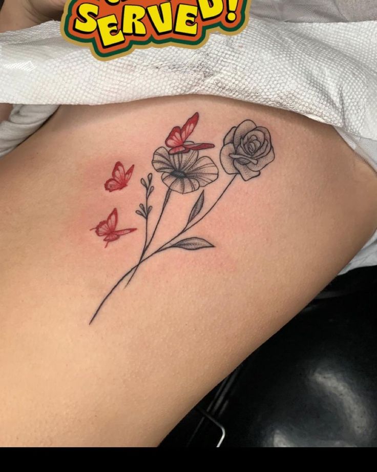 a woman's thigh with flowers and butterflies tattooed on her stomach, which reads sorry served