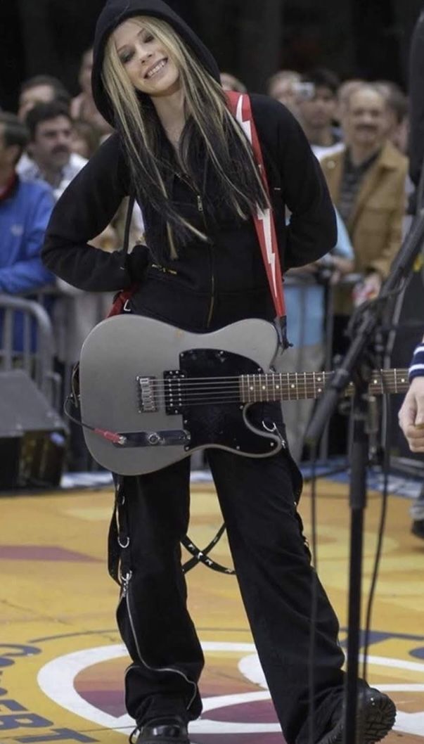 a woman standing in front of a microphone holding a guitar