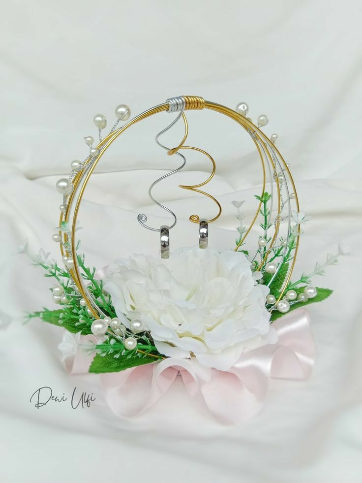 a white flower sitting in front of a gold hoop with two rings on it's side