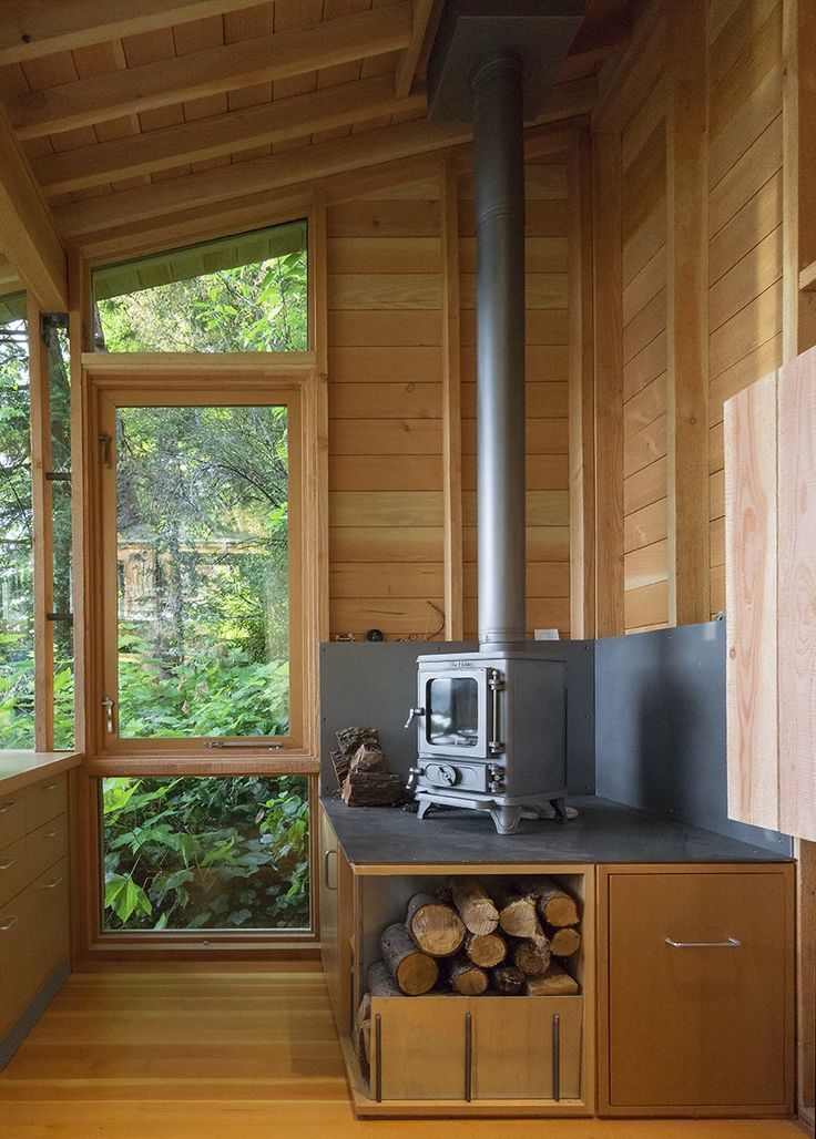 a stove in a wood cabin with lots of windows