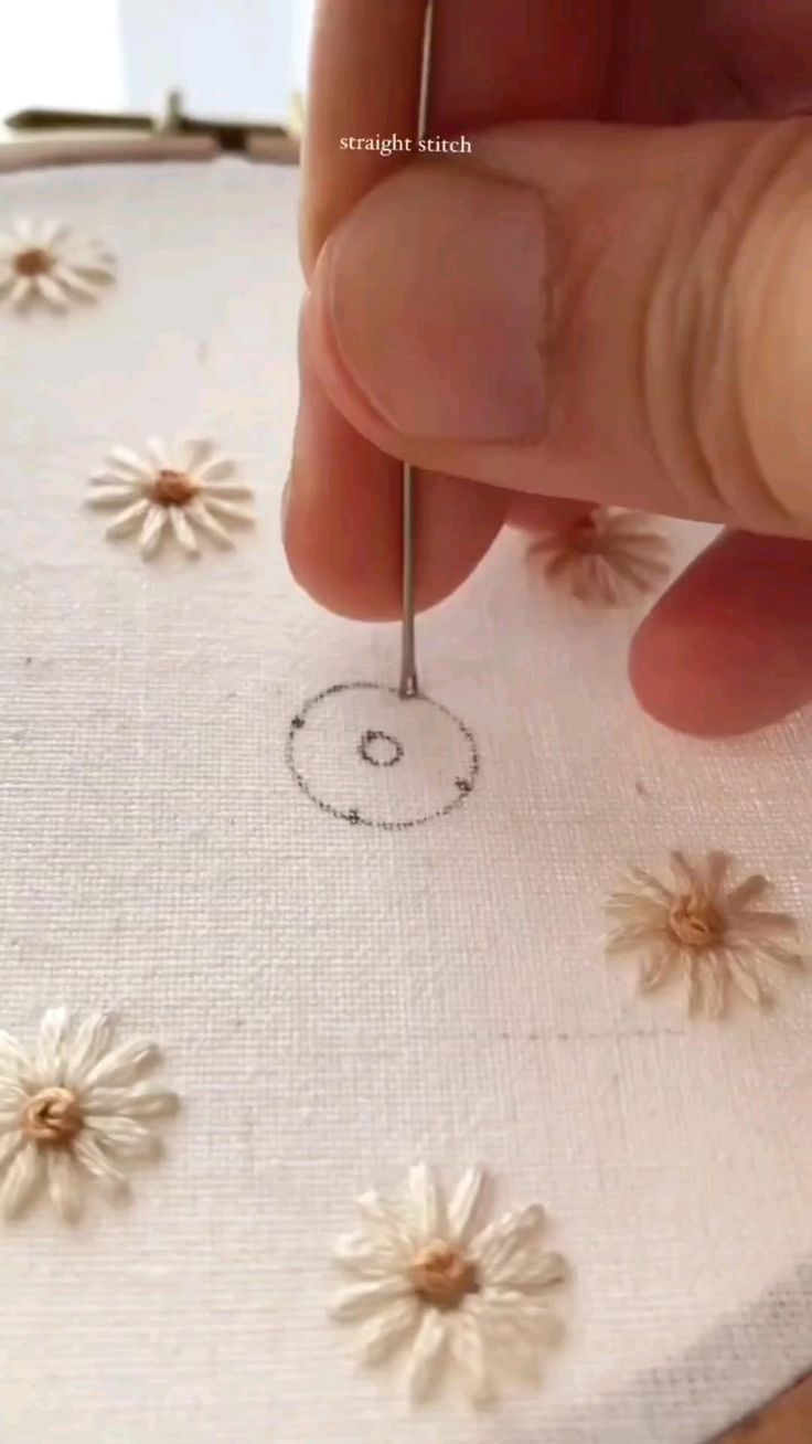 someone is stitching daisies on a piece of fabric