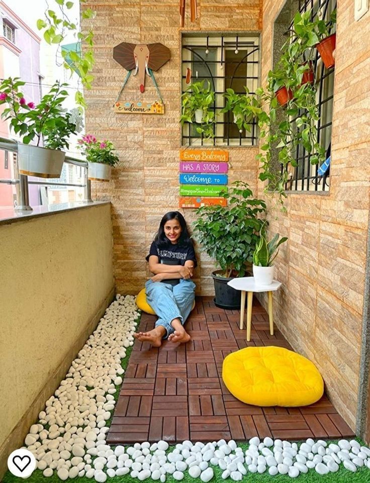 a woman sitting on top of a yellow chair in front of a brick wall and potted plants