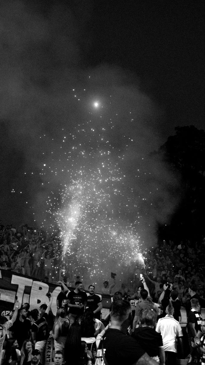 fireworks are lit up in the night sky as people watch and take pictures with their cell phones