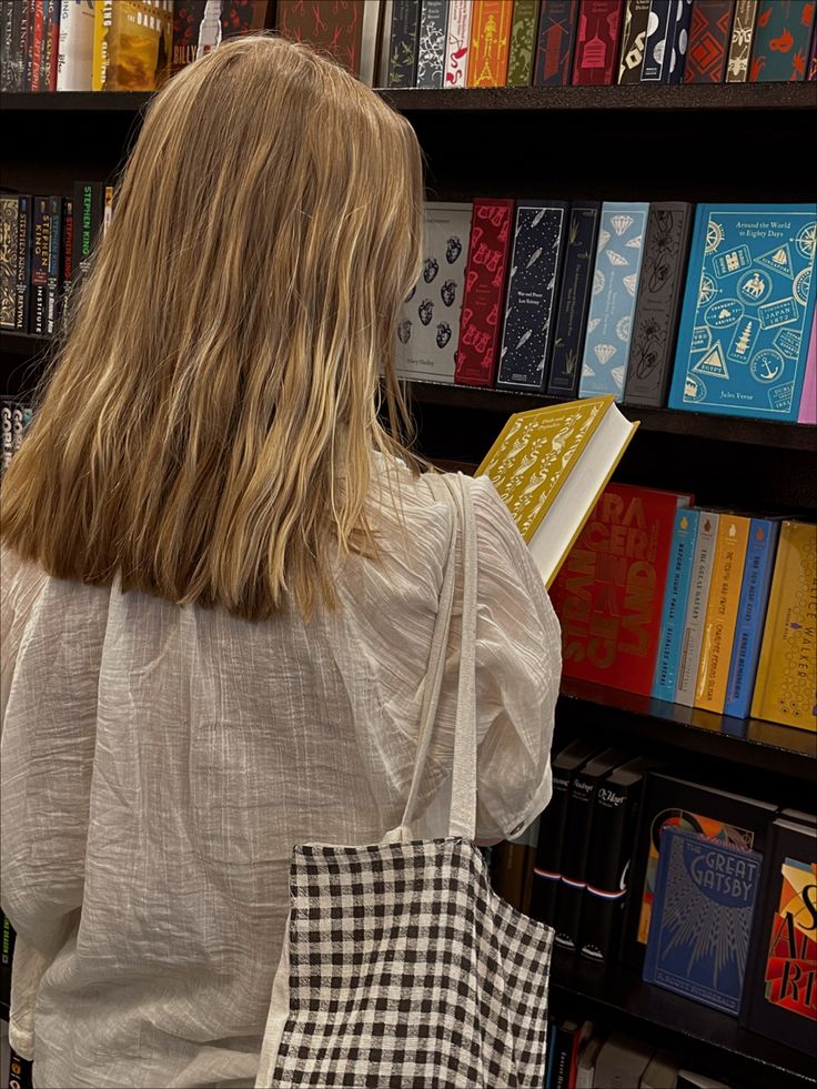 a woman is looking at books in a book store