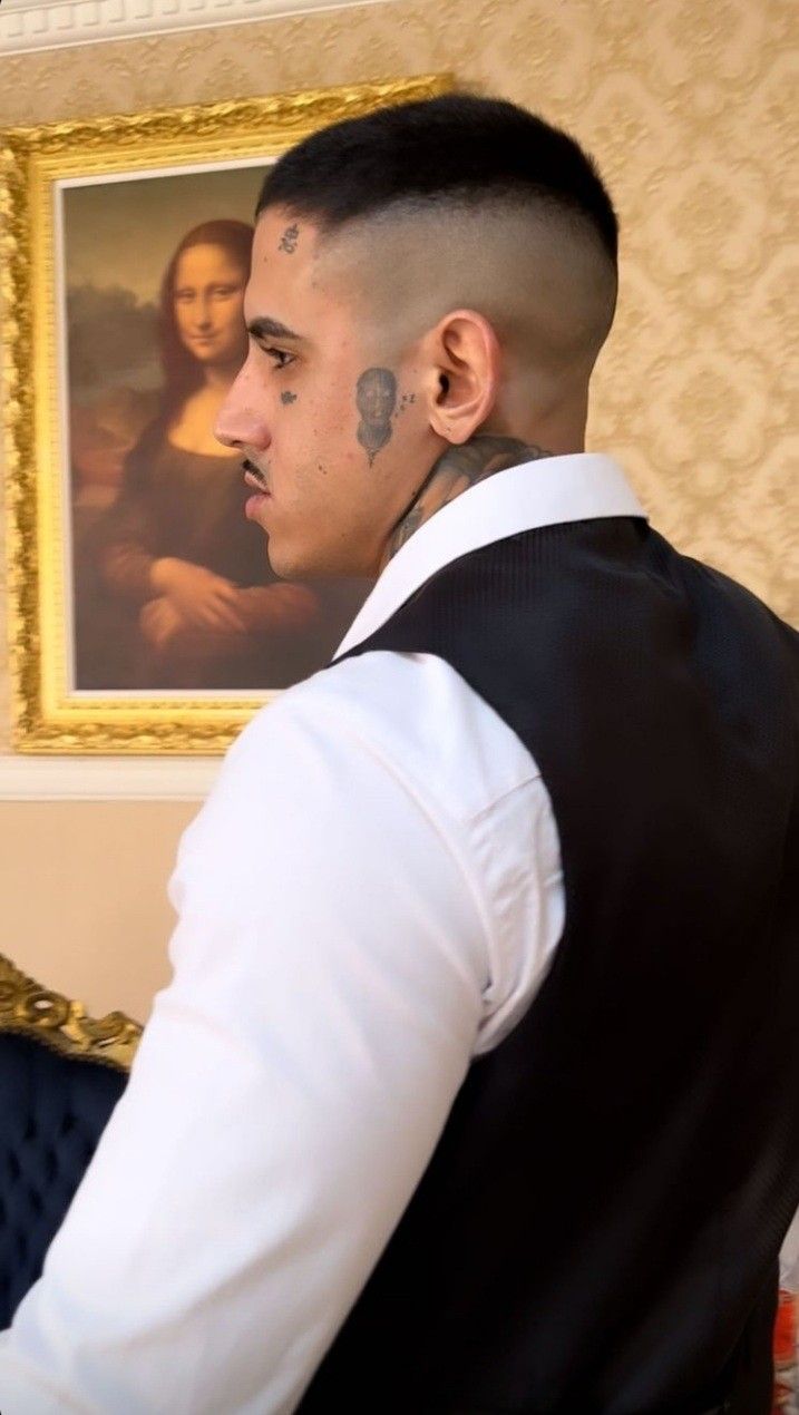 a man with tattoos standing in front of a painting