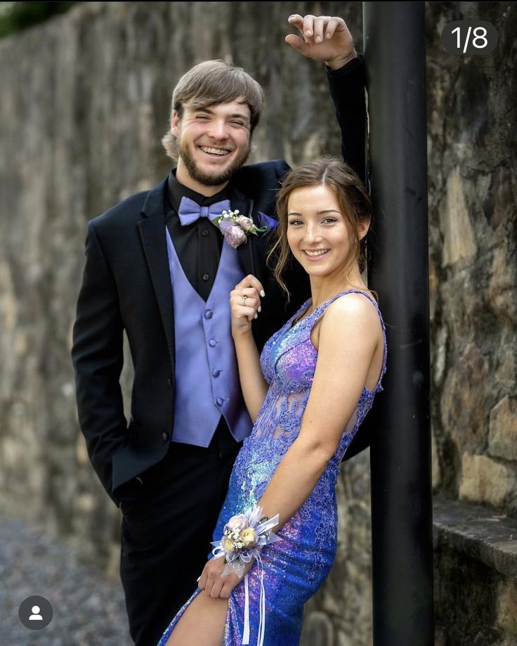 a man in a tuxedo standing next to a woman wearing a purple dress