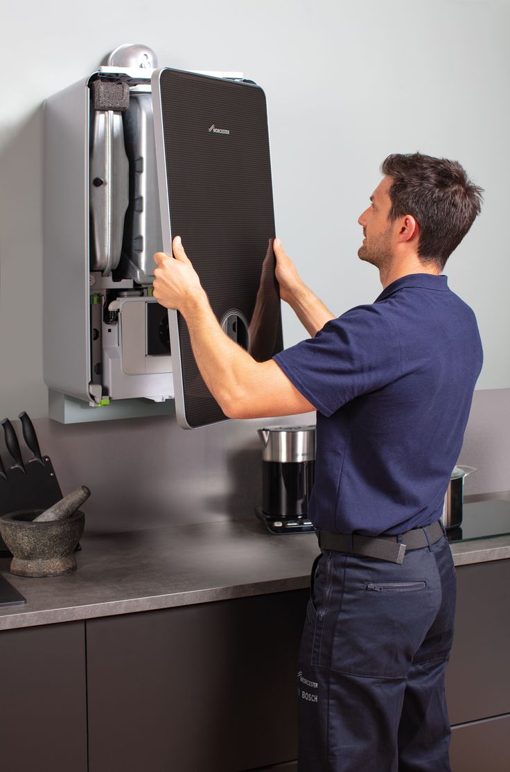 a man working on an appliance in the kitchen with his hand on it