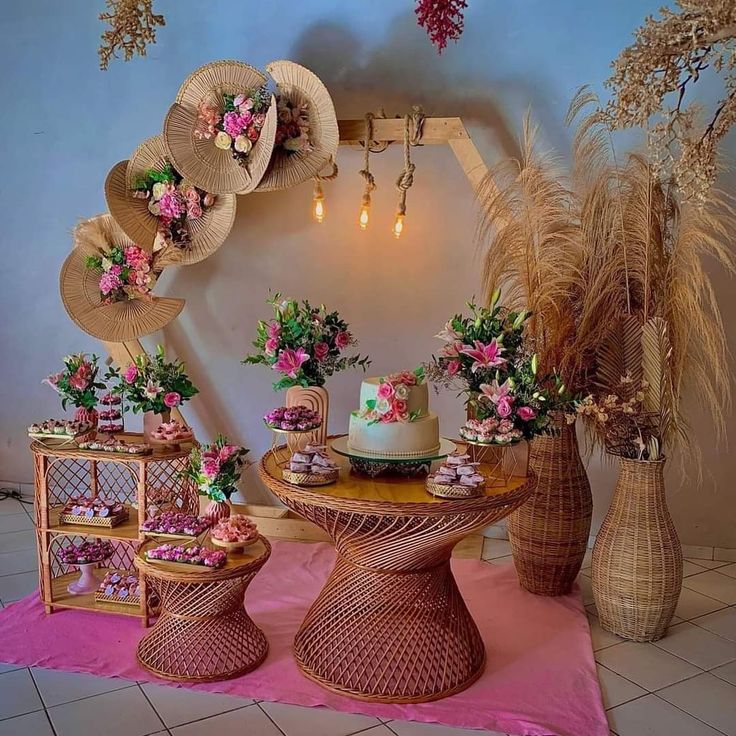 a table topped with cakes and flowers next to vases filled with plants on top of a pink rug