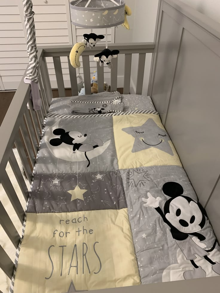 a baby crib with mickey mouse bedding on it's side and stars in the middle