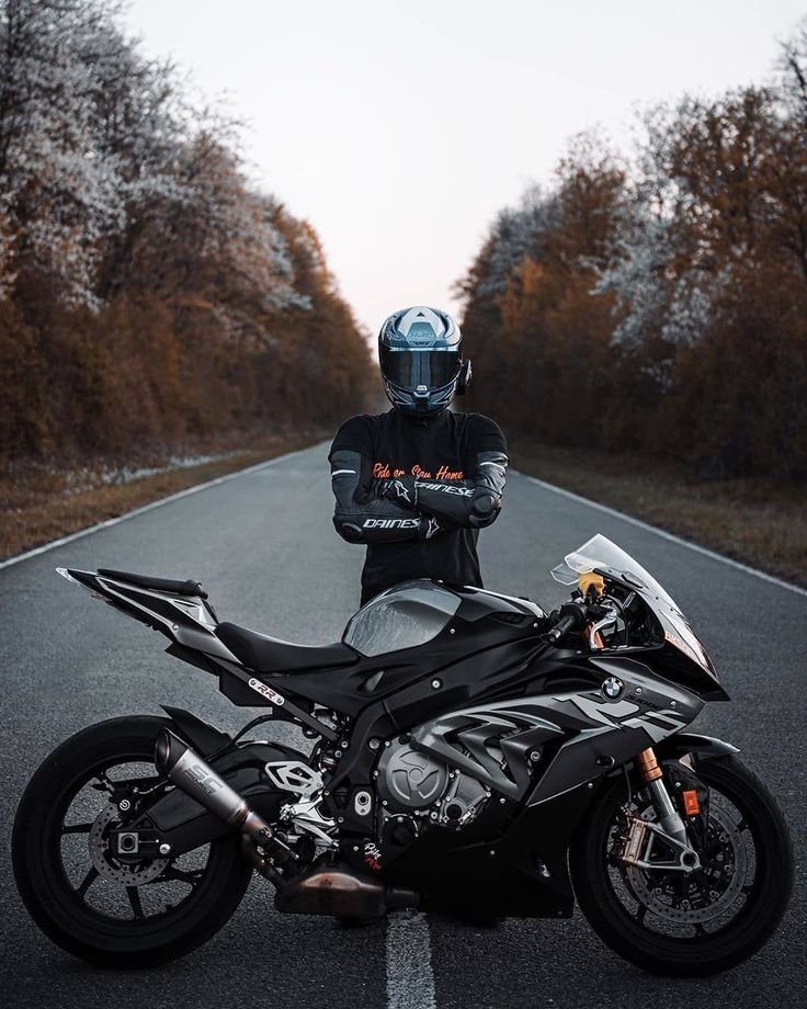 a person standing next to a motorcycle on the road