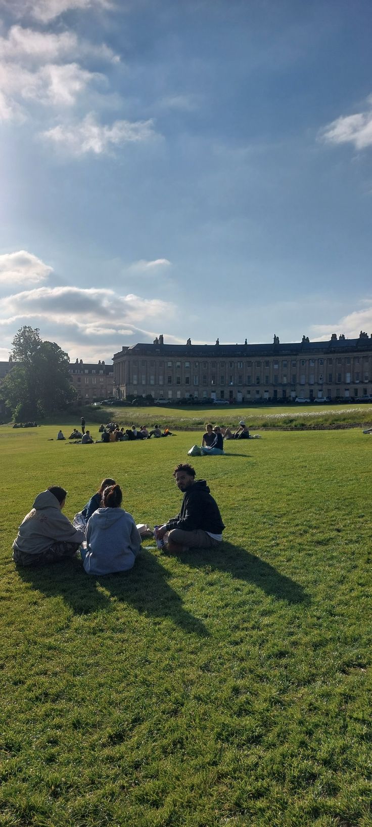 three people sitting on the grass in front of a building