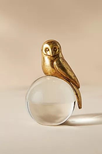 a gold bird figurine sitting on top of a glass ball