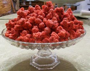 there is a glass bowl full of red candy flakes on top of the table