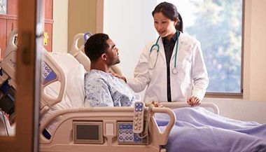 a nurse talking to a patient in a hospital bed