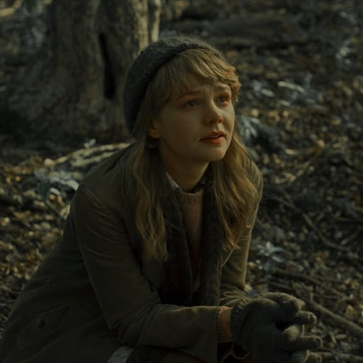 a woman sitting in the woods with her hands on her knees and looking at something