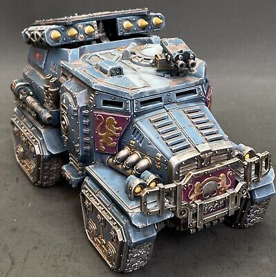 a painted warhammer vehicle sitting on top of a gray surface with gold trimmings