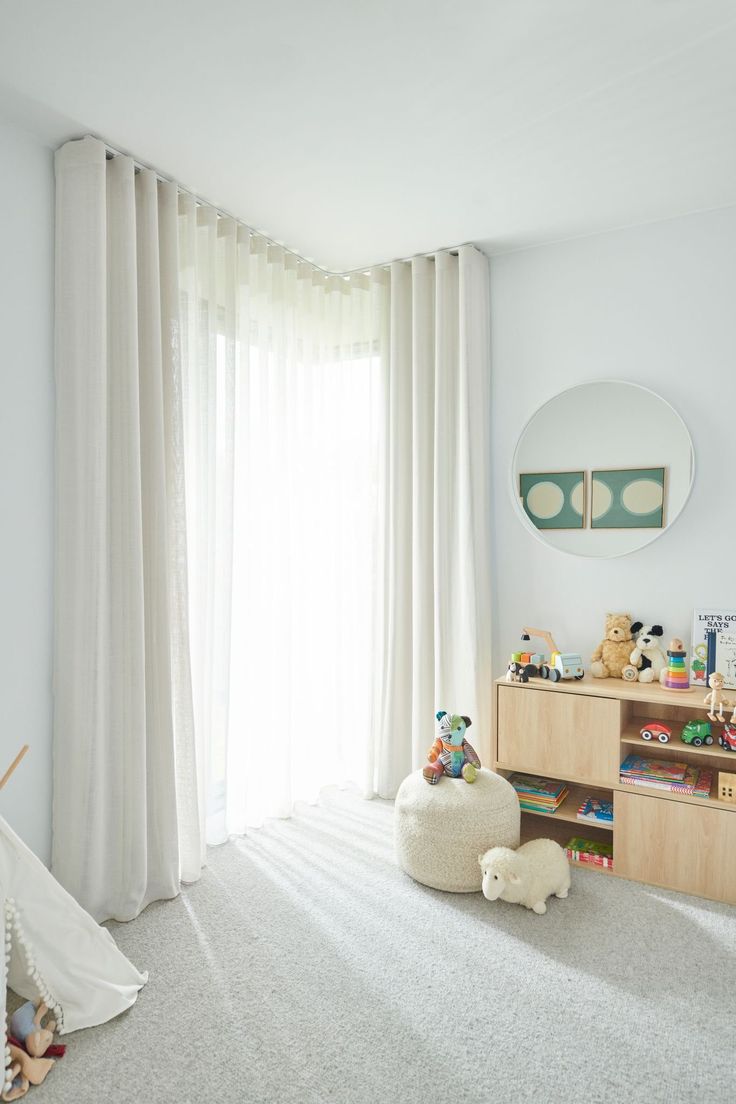 a child's room with white curtains and toys