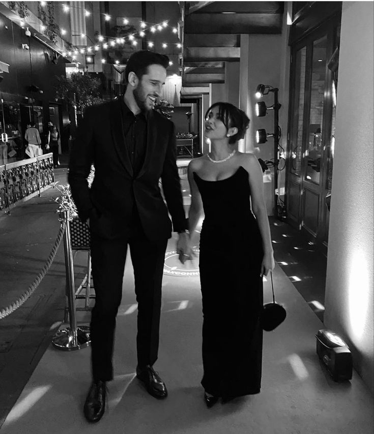 a man and woman walking down a hallway holding hands