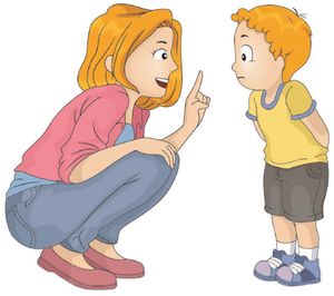 a woman kneeling down next to a little boy who is pointing at him with his finger