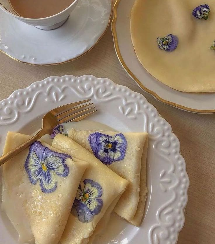 three crepes with blue pansies on them and a cup of coffee