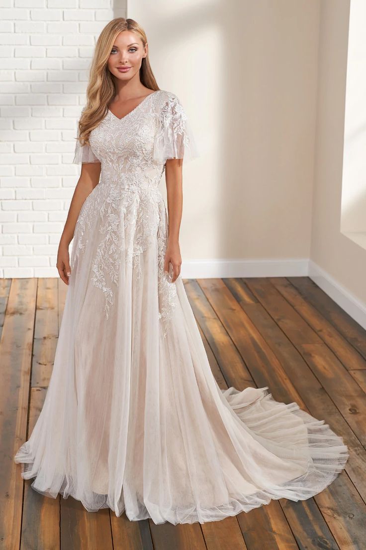 a woman in a wedding dress standing on a wooden floor