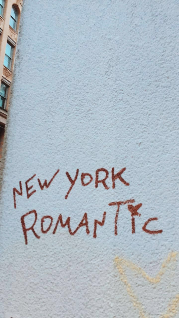 graffiti on the side of a building that says new york romantic written in red ink