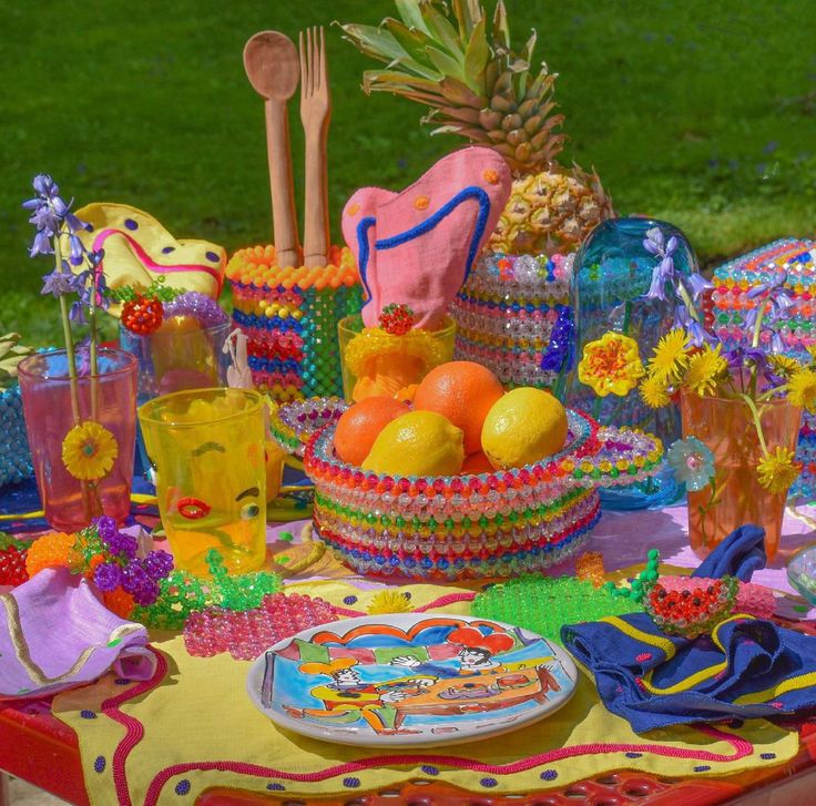 a table topped with lots of colorful food and decor on top of a grass covered field