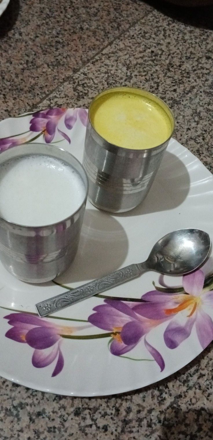 two cups and spoons sitting on a plate with purple flowers painted on the surface