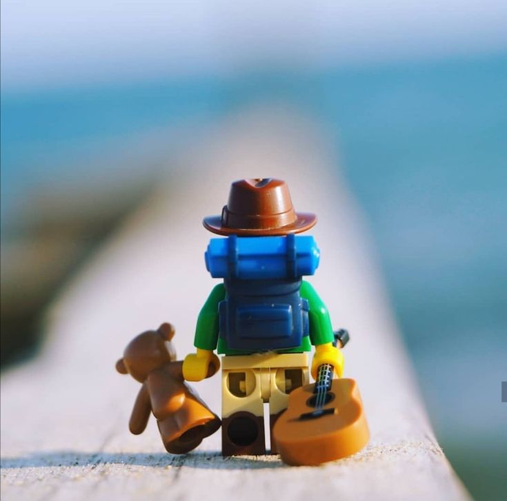 there is a lego man with a hat and a bear on the beach next to him