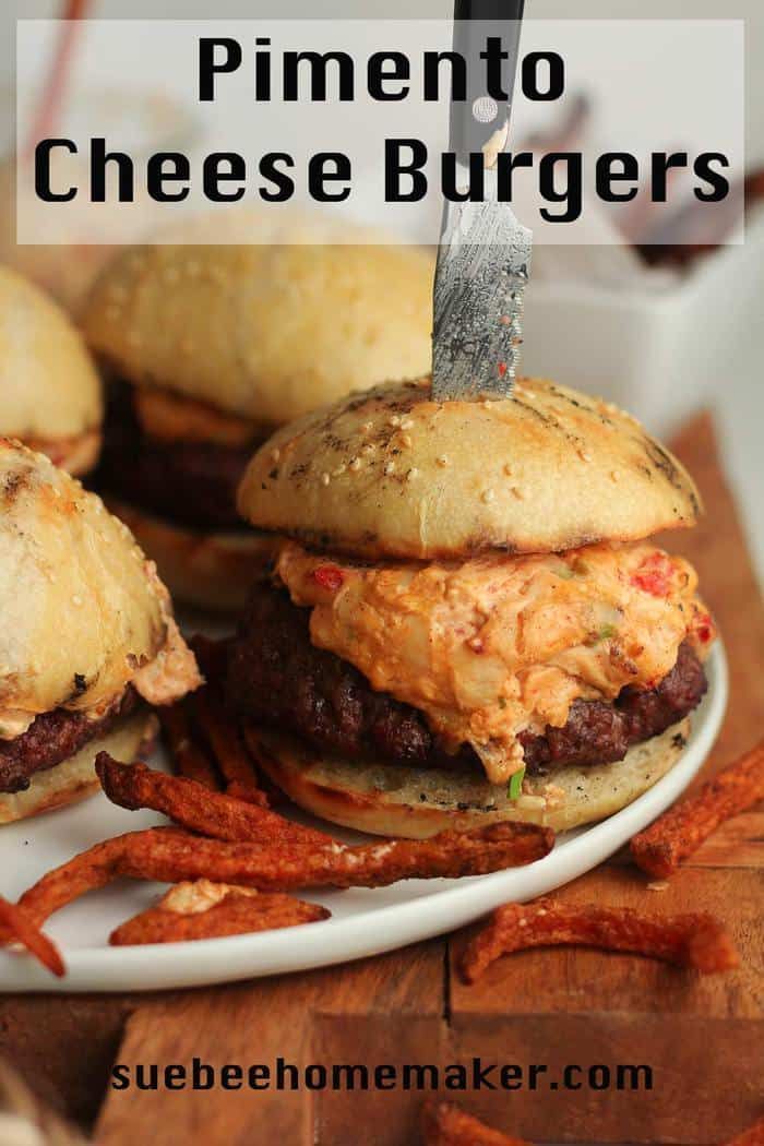 homemade cheeseburgers on a white plate with sweet potato fries in the foreground